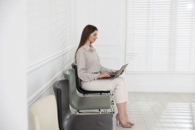 Photo of Woman with laptop waiting for appointment indoors