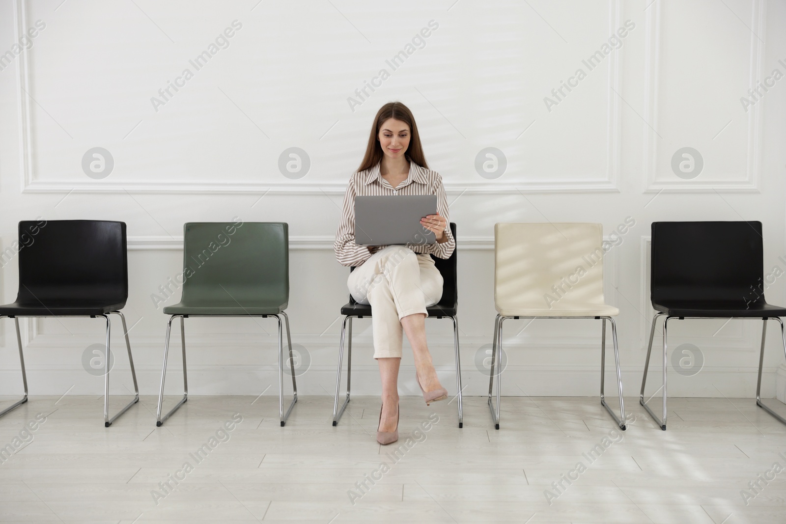 Woman with laptop waiting for appointment indoors Photo of Woman with laptop waiting for appointment indoors