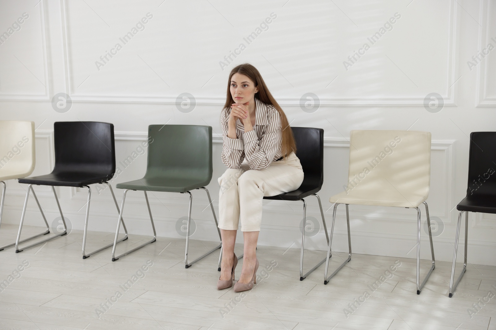 Woman sitting on chair and waiting for appointment indoors Photo of Woman sitting on chair and waiting for appointment indoors