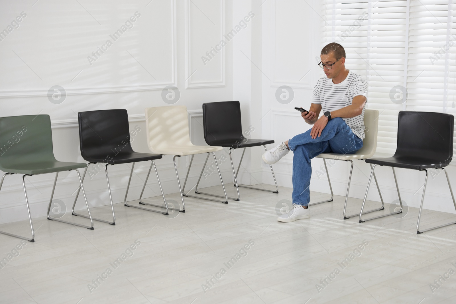 Man with smartphone waiting for appointment indoors Photo of Man with smartphone waiting for appointment indoors