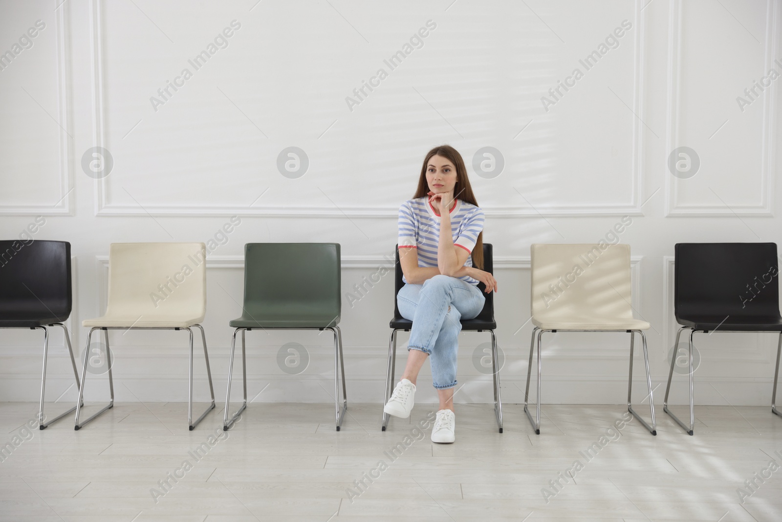Woman sitting on chair and waiting for appointment indoors Photo of Woman sitting on chair and waiting for appointment indoors