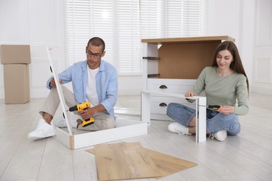 Photo of Couple assembling furniture on floor at home