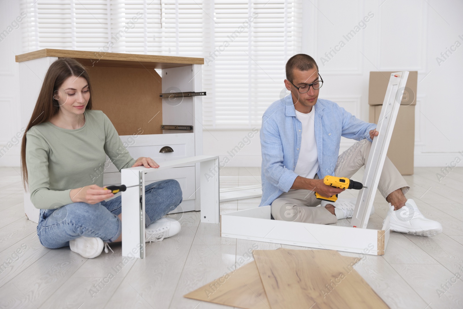 Couple assembling furniture on floor at home Photo of Couple assembling furniture on floor at home