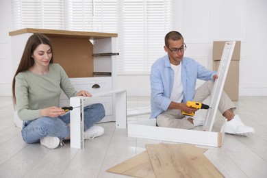 Photo of Couple assembling furniture on floor at home