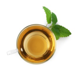 Photo of Aromatic lemon balm tea in glass cup and fresh leaves isolated on white, top view