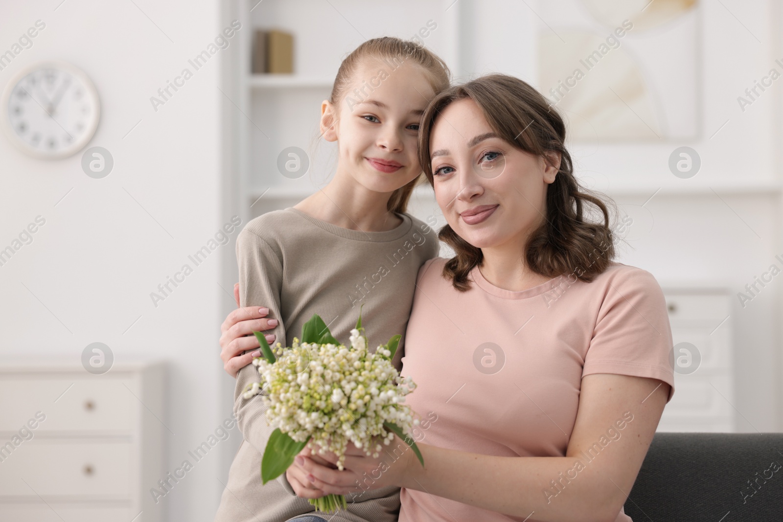 Girl giving her mother beautiful bouquet of lily-of-the-valley flowers at home Photo of Girl giving her mother beautiful bouquet of lily-of-the-valley flowers at home