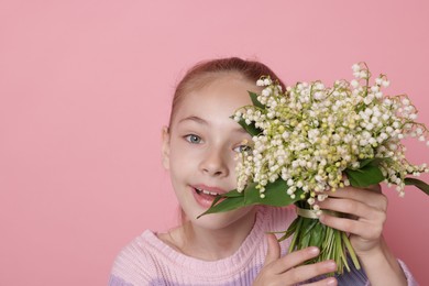 Photo of Girl with bouquet of beautiful lily-of-the-valley flowers on light pink background. Space for text
