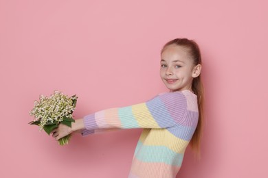 Photo of Girl with bouquet of beautiful lily-of-the-valley flowers on light pink background. Space for text