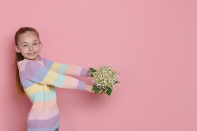 Photo of Girl with bouquet of beautiful lily-of-the-valley flowers on light pink background. Space for text