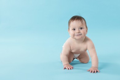 Photo of Cute little baby crawling on light blue background. Space for text