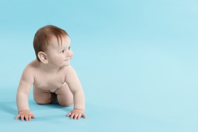 Photo of Cute little baby crawling on light blue background. Space for text