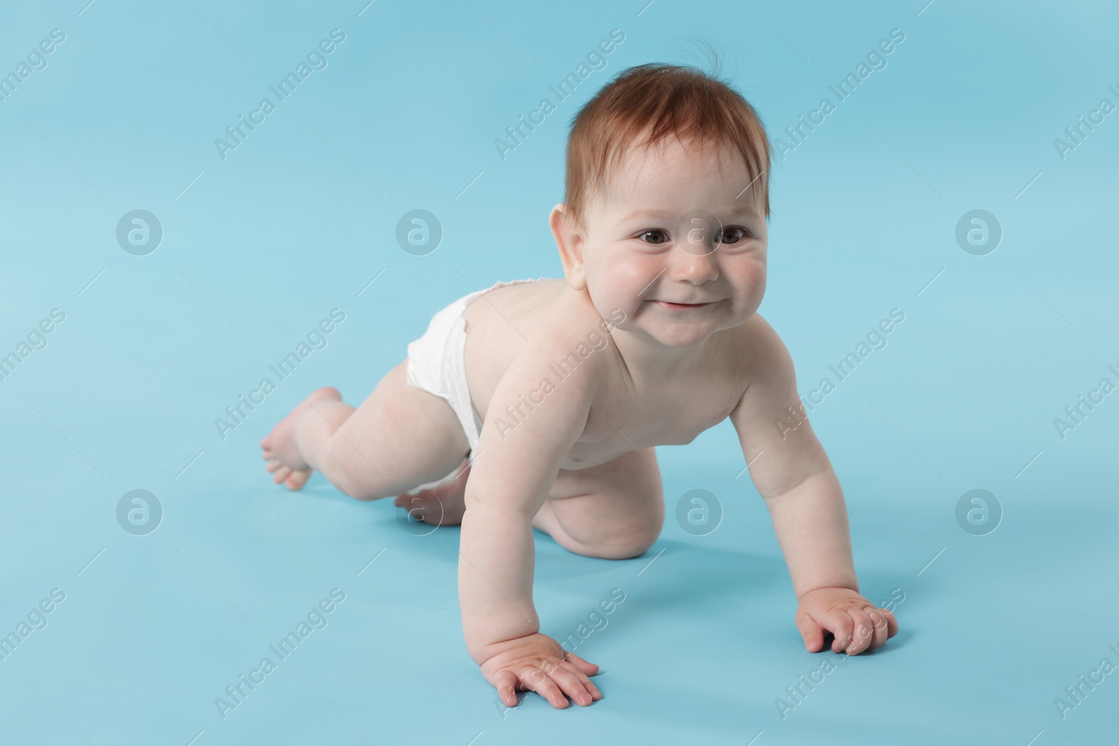 Cute little baby crawling on light blue background Photo of Cute little baby crawling on light blue background