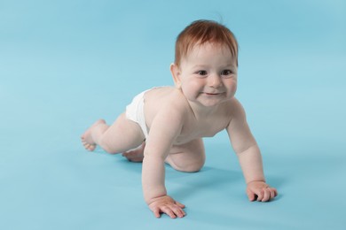 Photo of Cute little baby crawling on light blue background