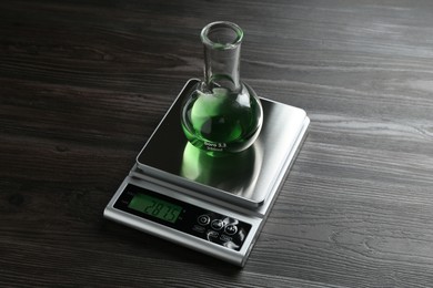 Photo of Laboratory scale with flask of sample on wooden table