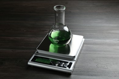 Photo of Laboratory scale with flask of sample on wooden table