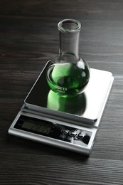 Photo of Laboratory scale with flask of sample on wooden table
