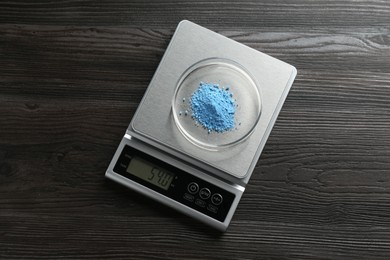 Photo of Laboratory scale with Petri dish of sample on wooden table, top view
