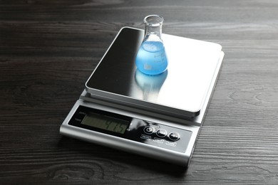 Photo of Laboratory scale with flask of sample on wooden table, closeup