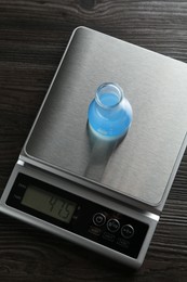 Photo of Laboratory scale with flask of sample on wooden table, top view