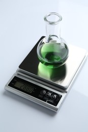 Photo of Laboratory scale with flask of sample on white background