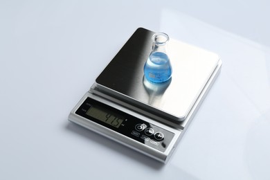 Photo of Laboratory scale with flask of sample on white background