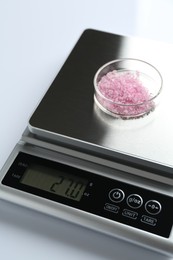 Photo of Laboratory scale with Petri dish of sample on white background, closeup