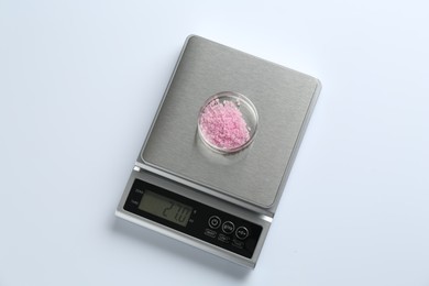 Photo of Laboratory scale with Petri dish of sample on white background, top view