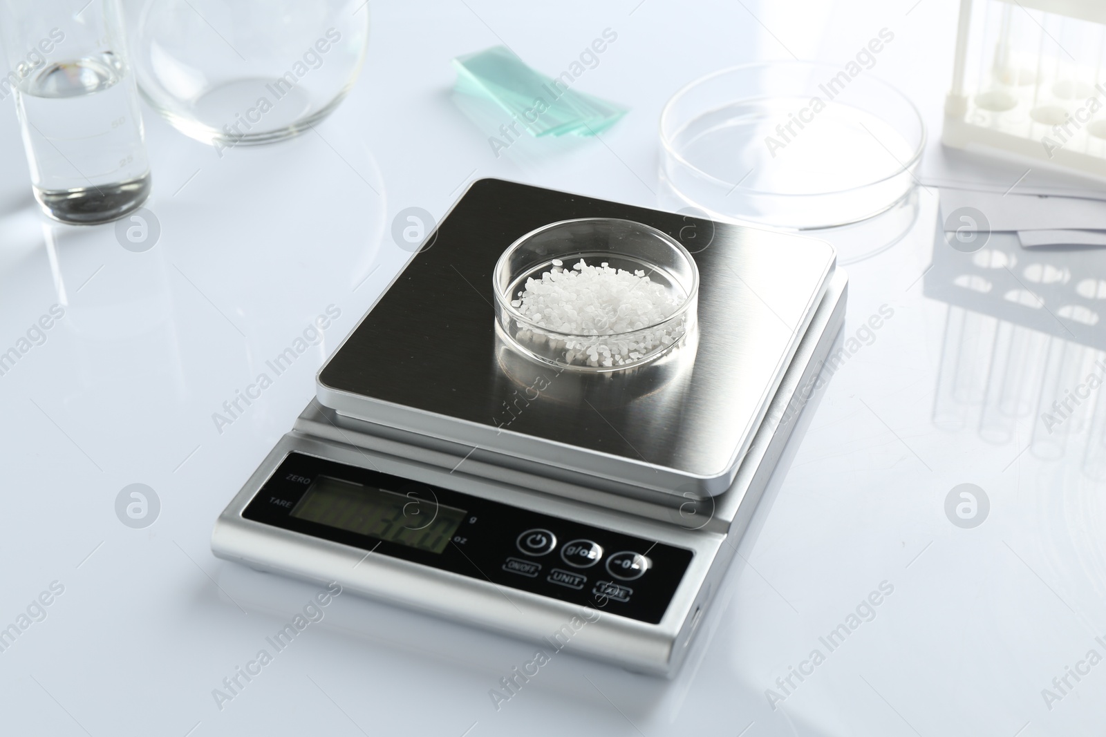 Scale with Petri dish of sample and other laboratory equipment on white background, closeup Photo of Scale with Petri dish of sample and other laboratory equipment on white background, closeup