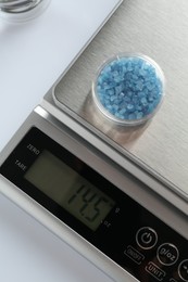 Photo of Laboratory scale with Petri dish of sample on white background, top view