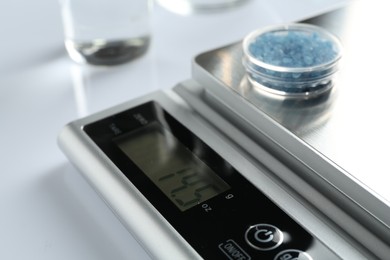 Photo of Laboratory scale with Petri dish of sample on white background, closeup