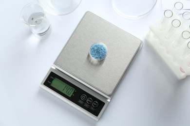 Photo of Scale with Petri dish of sample and other laboratory equipment on white background, flat lay