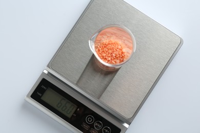 Photo of Laboratory scale with beaker of sample on white background, top view