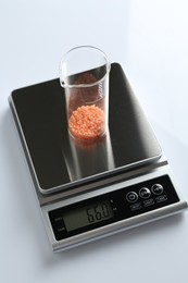 Photo of Laboratory scale with beaker of sample on white background, above view