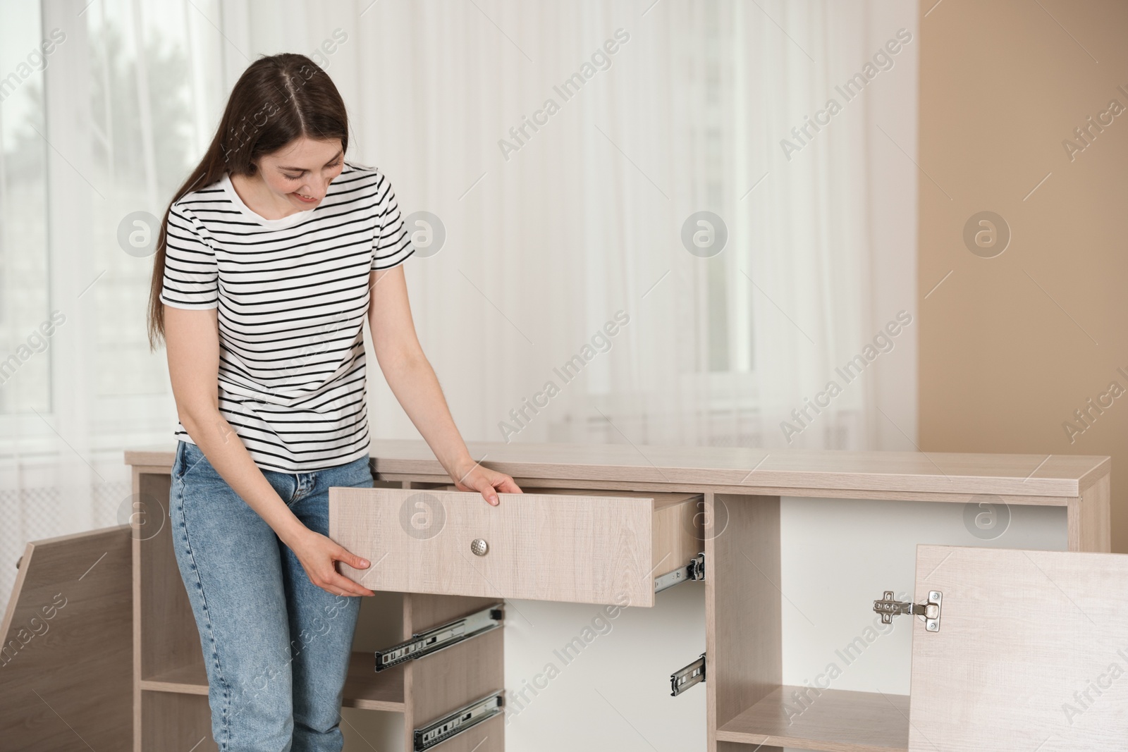 Self assembly furniture. Smiling woman looking at drawer indoors Photo of Self assembly furniture. Smiling woman looking at drawer indoors
