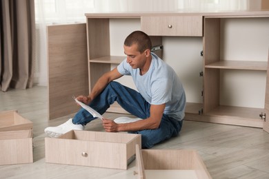 Photo of Man with manual assembling furniture on floor at home