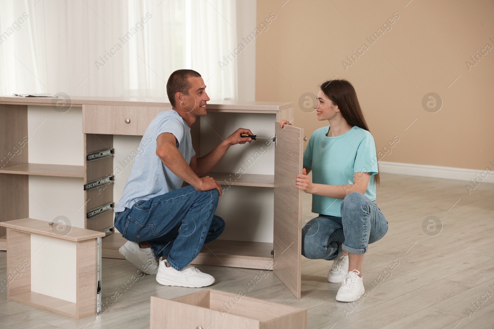 Happy couple assembling furniture on floor at home Photo of Happy couple assembling furniture on floor at home