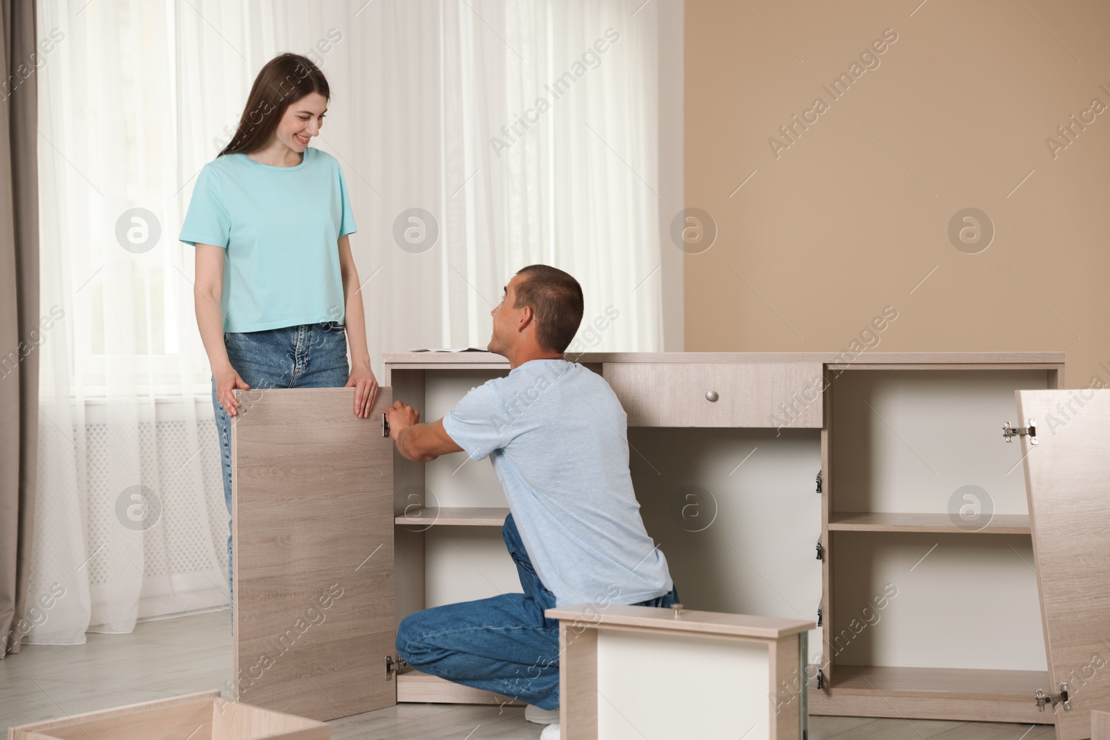 Happy couple assembling furniture on floor at home Photo of Happy couple assembling furniture on floor at home
