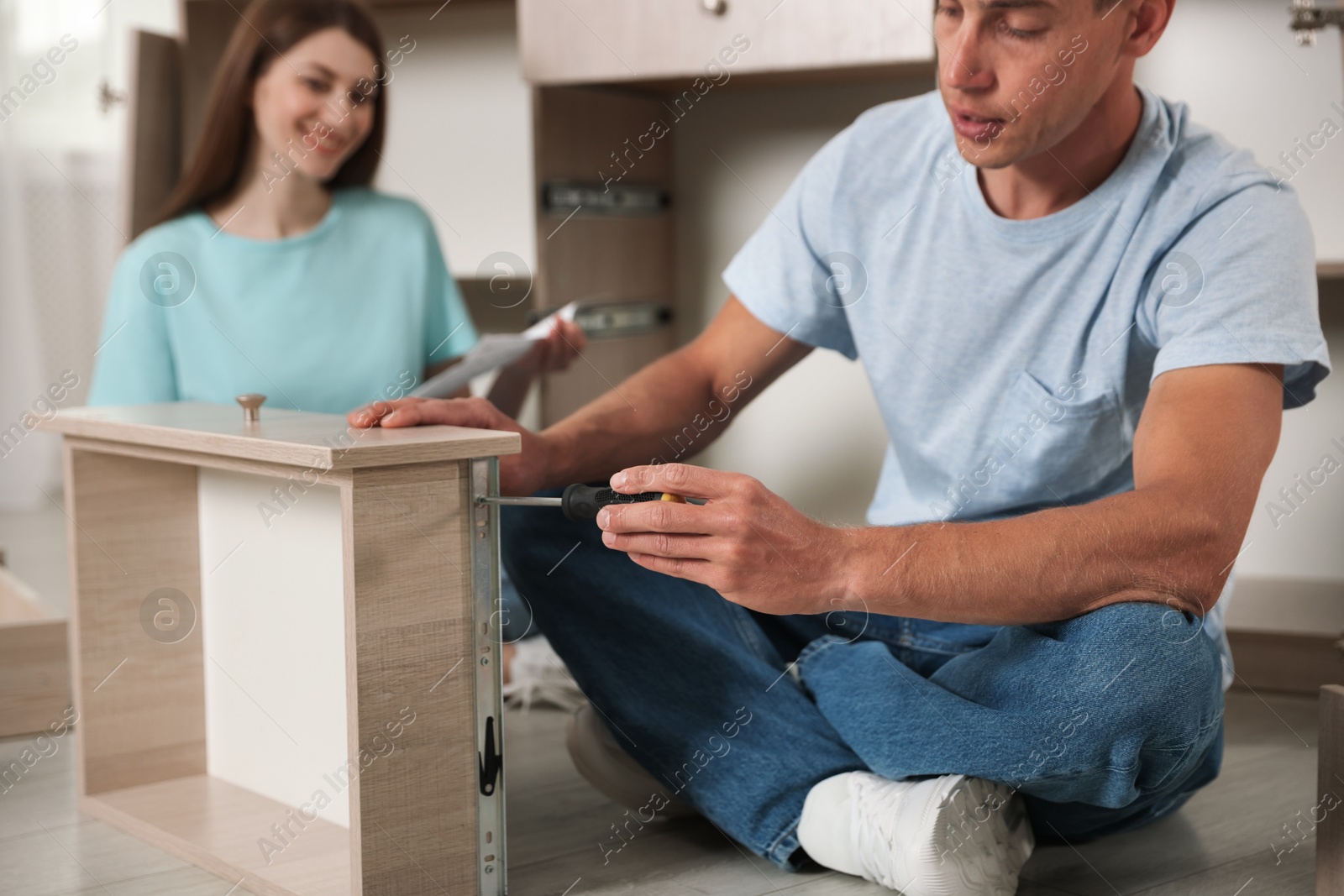Couple assembling furniture with screwdriver on floor at home, selective focus Photo of Couple assembling furniture with screwdriver on floor at home, selective focus