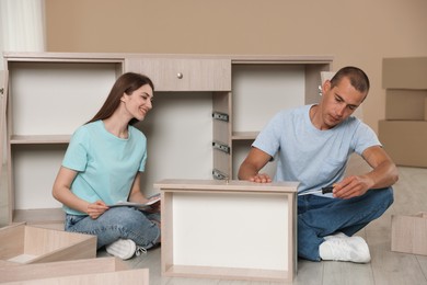 Photo of Couple assembling furniture on floor at home