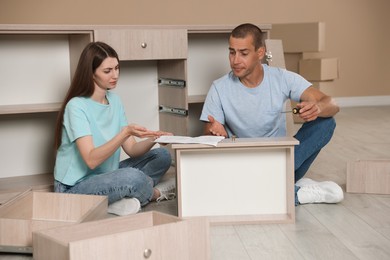 Photo of Couple with manual assembling furniture on floor at home