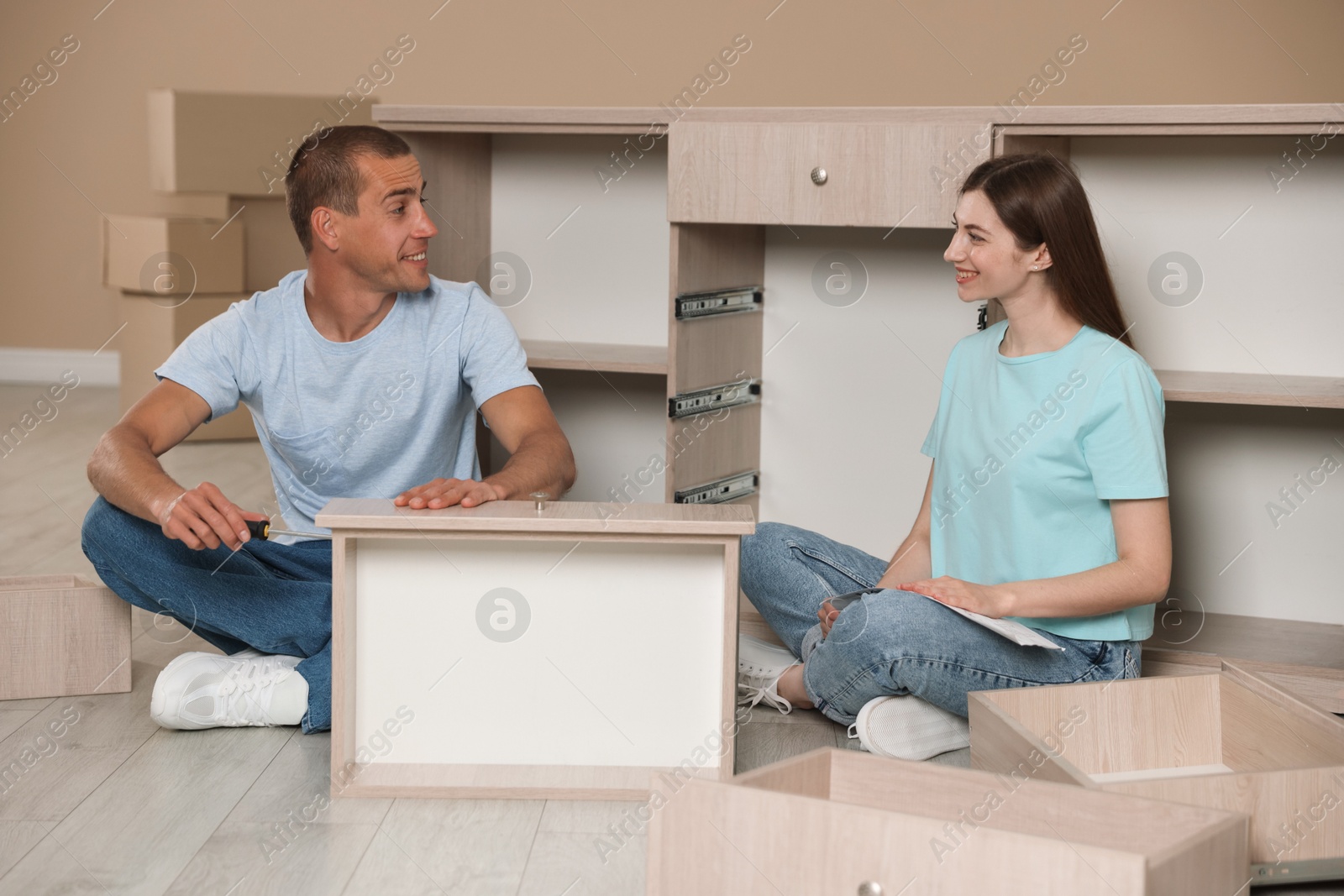 Happy couple assembling furniture on floor at home Photo of Happy couple assembling furniture on floor at home