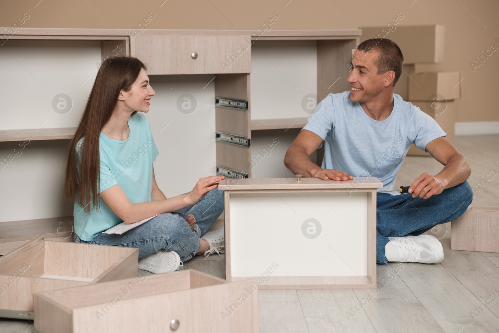 Happy couple assembling furniture on floor at home Photo of Happy couple assembling furniture on floor at home