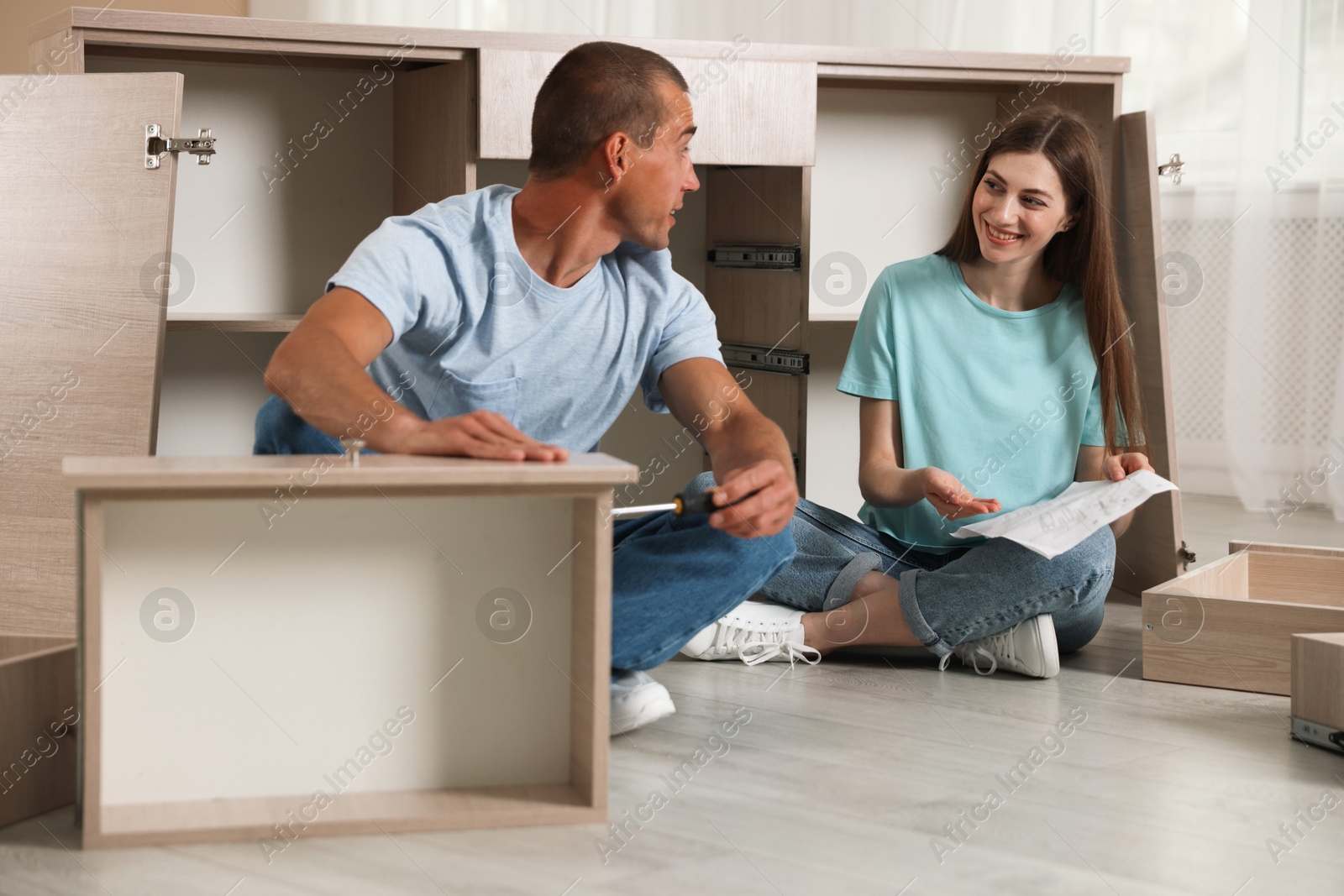 Happy couple assembling furniture on floor at home Photo of Happy couple assembling furniture on floor at home