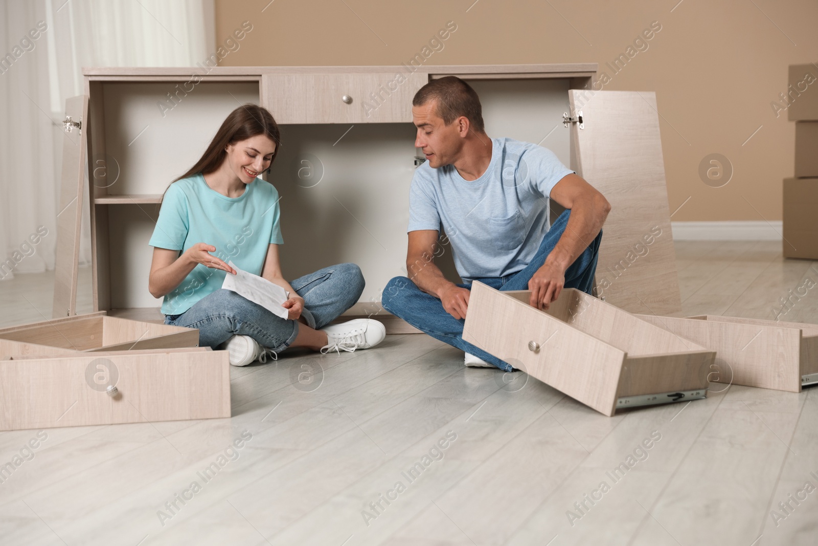Happy couple with manual assembling furniture on floor at home Photo of Happy couple with manual assembling furniture on floor at home