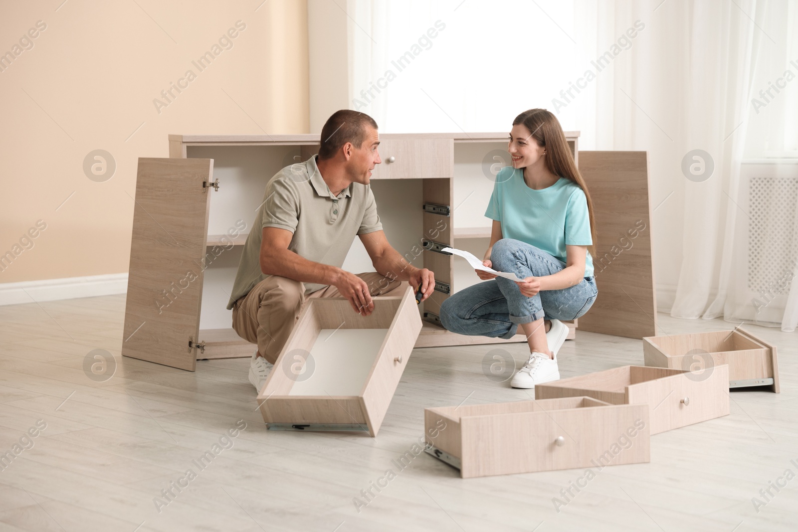 Happy couple with manual assembling furniture on floor at home Photo of Happy couple with manual assembling furniture on floor at home