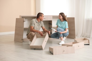 Photo of Happy couple with manual assembling furniture on floor at home