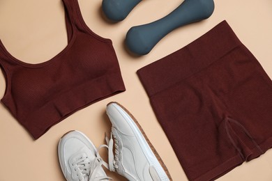 Photo of Sportswear, dumbbells and sneakers on beige background, flat lay