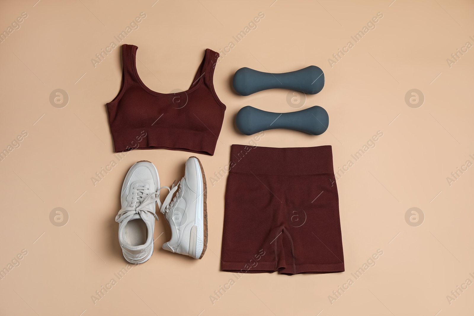 Sportswear, dumbbells and sneakers on beige background, flat lay Photo of Sportswear, dumbbells and sneakers on beige background, flat lay