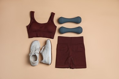 Photo of Sportswear, dumbbells and sneakers on beige background, flat lay