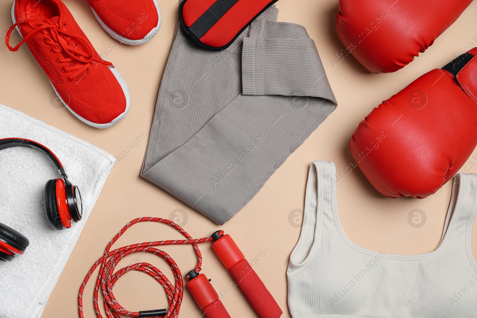 Sportswear, gloves, skipping rope, headphones and towel on beige background, flat lay Photo of Sportswear, gloves, skipping rope, headphones and towel on beige background, flat lay